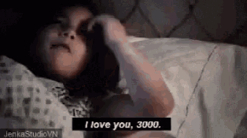 a woman is laying in bed and talking on a cell phone .