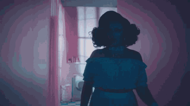 a woman in a white dress is standing in a hallway with a pink wall