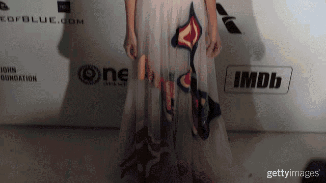 a woman stands in front of a wall that says imdb
