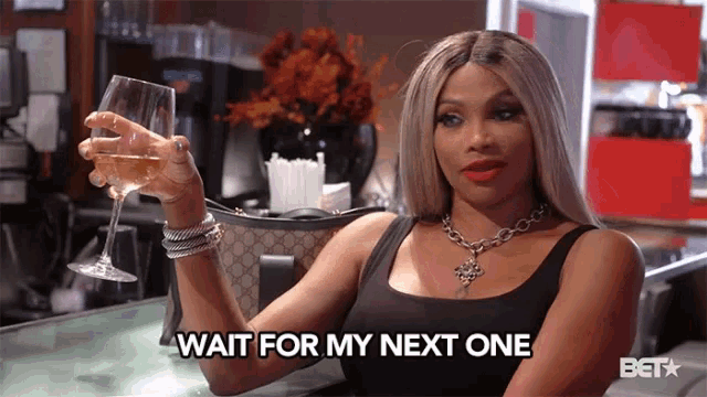 a woman is holding a wine glass and saying wait for my next one