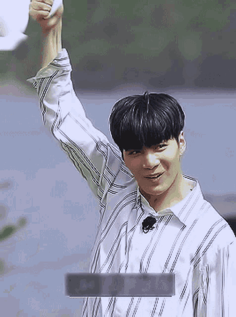 a young man wearing a striped shirt holds his arm up in the air