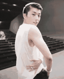 a man wearing a headband and a white tank top is standing with his hands on his hips