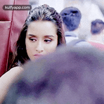 a woman is sitting next to a man on a plane and looking over his shoulder .