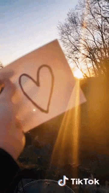 a person is holding a paper with a heart drawn on it