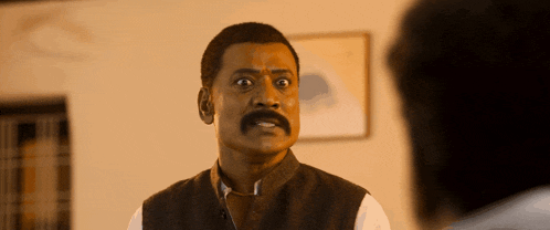 a man with a mustache looks at the camera with his mouth open