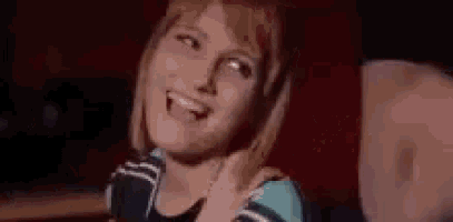 a close up of a woman laughing and smiling while sitting at a table .