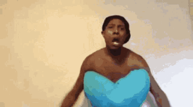 a shirtless man is holding a blue heart shaped pillow in his hands .