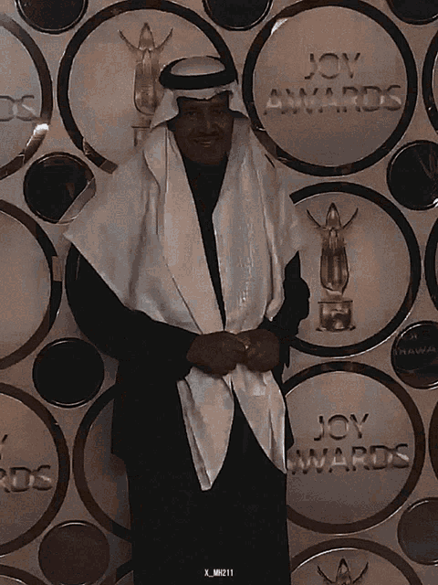 a man stands in front of a wall with joy awards written on it