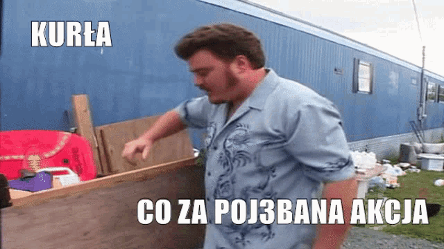 a man in a blue shirt is standing in front of a blue trailer with the words kurla co za poj3bana akcija on the bottom
