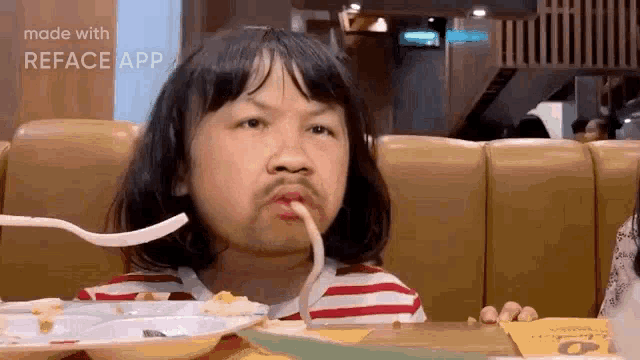 a little girl is sitting at a table eating spaghetti with a fork .