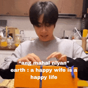a man is opening an orange box with the words " ang mahal niyan " on the top