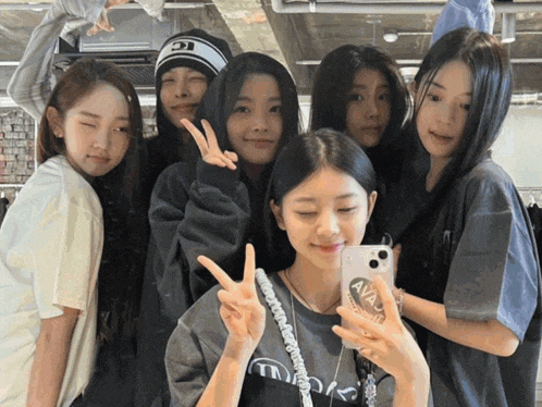 a group of girls are posing for a picture and one girl is holding a phone with the word avalanche on it