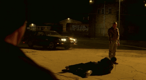 a man standing next to a man laying on the ground in front of a truck that says sub on the side