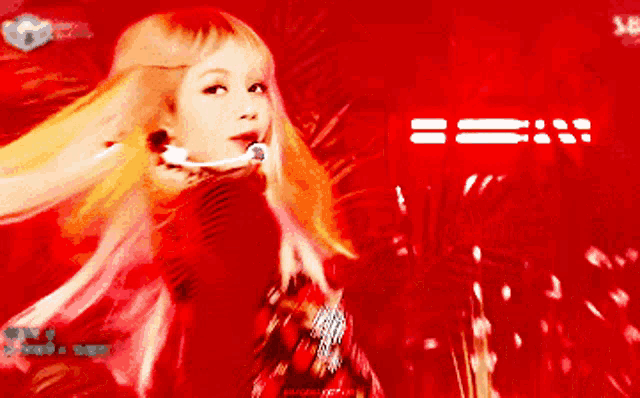a woman with blonde hair is standing in front of a red background that says sb