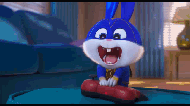 a blue and white cartoon rabbit is sitting on a table with its mouth open