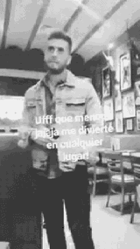 a man in a denim jacket is standing in a restaurant with a caption .