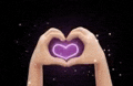 a pair of hands making a heart shape with a purple heart coming out of them .