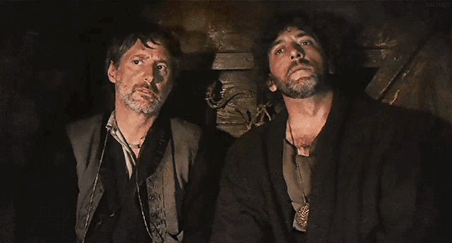 two men are sitting next to each other in a dark room