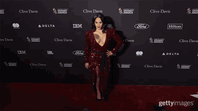 a woman in a red dress is standing in front of a wall that says ' clive davis ' on it