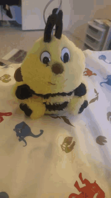 a stuffed bee is laying on a bed with animals on it