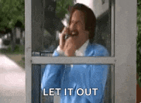 a man in a blue jacket is talking on a cell phone in a phone booth .
