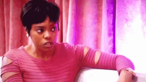 a woman in a pink dress is sitting on a couch .