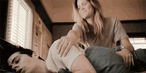a woman is putting her hand on a man 's back while he sleeps
