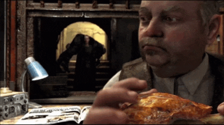 a man is eating a piece of food in front of a lamp and a book that says ' a ' on it