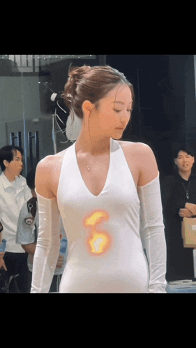 a woman wearing a white dress with a flame on her chest