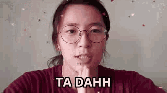 a woman wearing glasses and a red shirt is making a funny face .