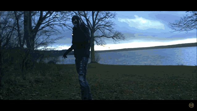 a person is standing in front of a body of water with a watermark on the bottom of the screen
