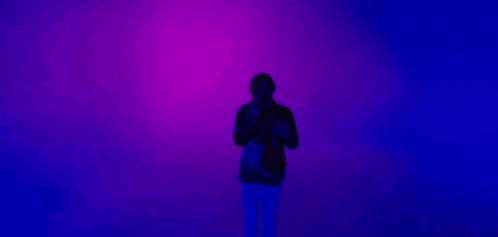 a man is standing in front of a blue and purple background .