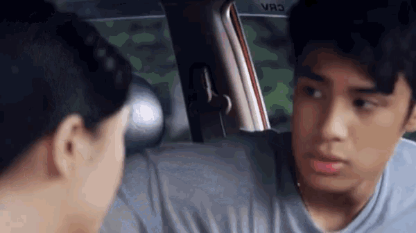 a boy and a girl are looking at each other in a car .