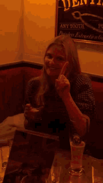 a woman sitting at a table in front of a sign that says dent any tooth