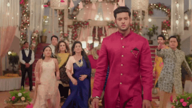 a man in a red suit walks in front of a group of people
