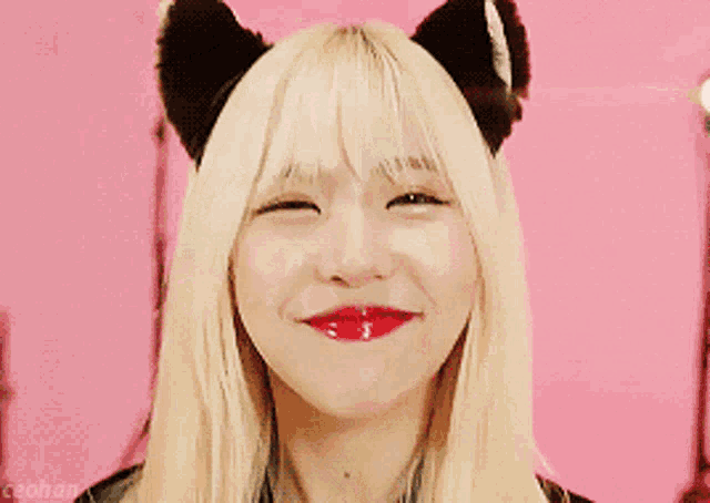 a woman with blonde hair and black cat ears smiles