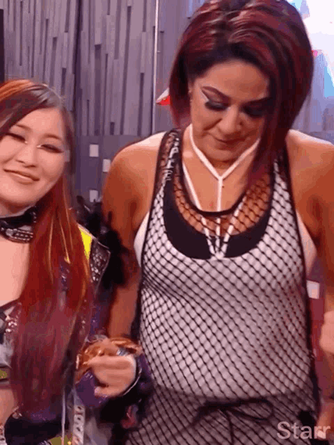 two women are standing next to each other and one of them is wearing a fishnet tank top