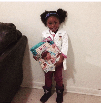 a little girl dressed up as doc mcstuffins holds a book
