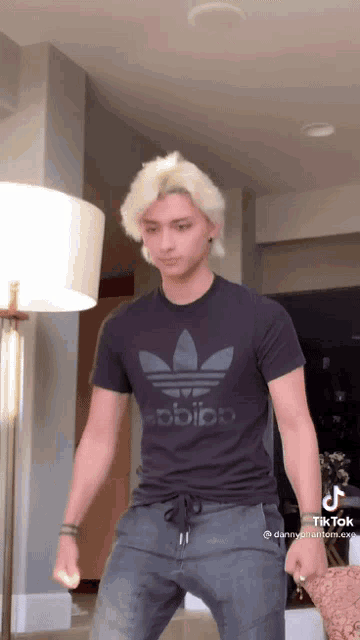 a man wearing a black adidas shirt is standing in a room
