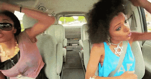 two women are dancing in the back seat of a van