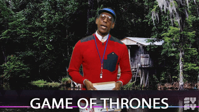 a man in a red sweater stands in front of a game of thrones poster