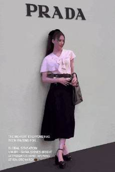 a woman is standing in front of a prada poster