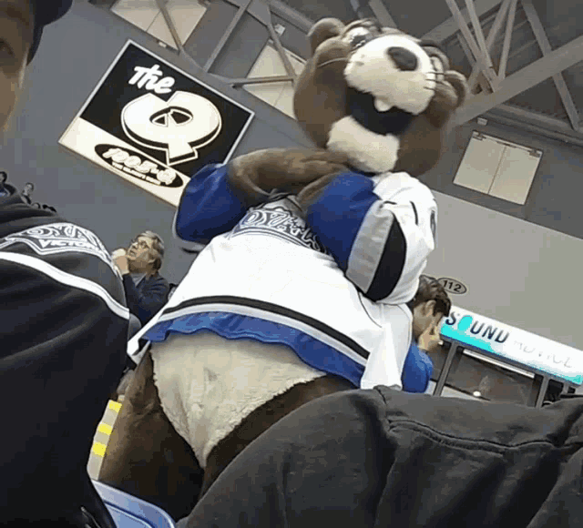 a mascot in front of a sign that says the q on it