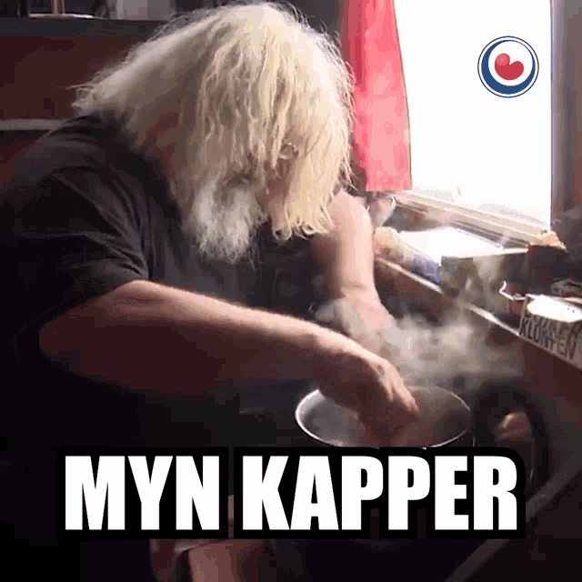a man with a beard is cooking in a pot with the word myn kapper above him