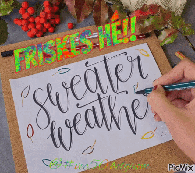 a person is writing the words sweater weather on a piece of paper