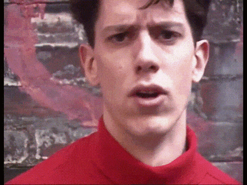 a man wearing a red turtleneck sweater is making a funny face