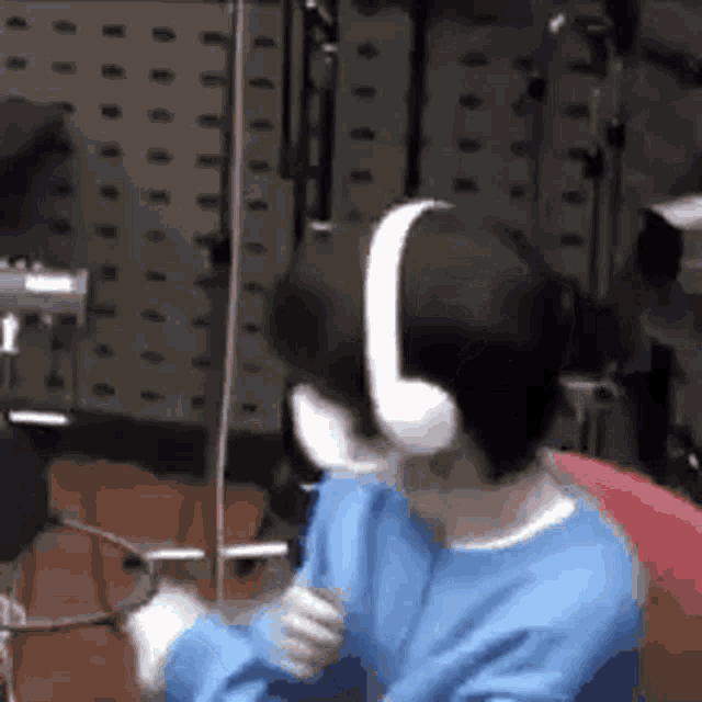 a person wearing headphones is sitting in a chair in a recording studio .