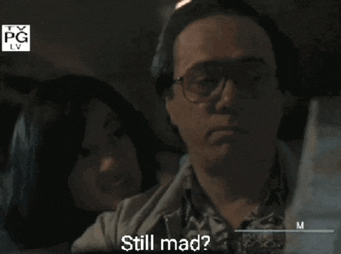 a man with glasses is sitting next to a woman who is asking him if he 's still mad