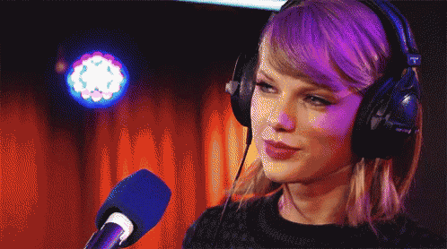 a woman is wearing headphones and talking into a microphone with the letter t on it