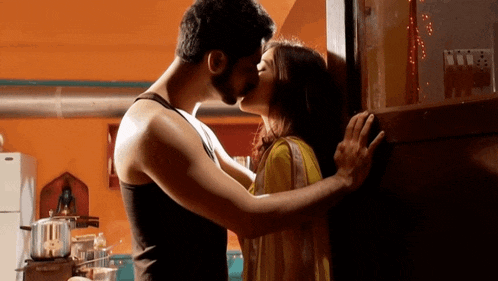 a man and a woman kissing on a wall in a kitchen